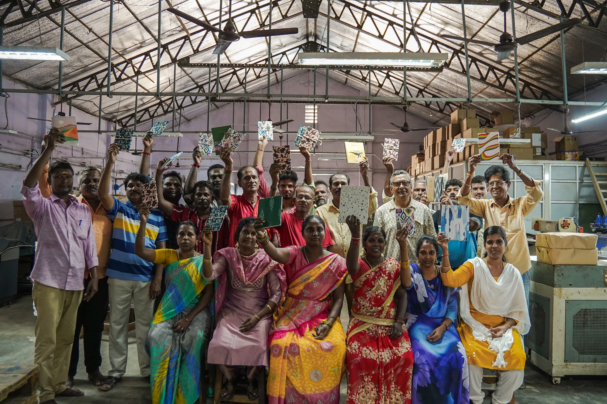 The bindery team standing together in the workshop, each holding up a finished notebook